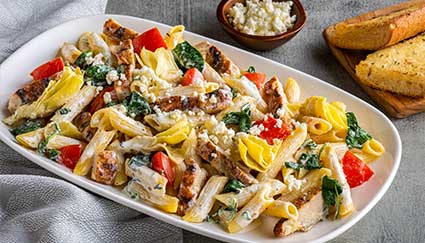 Creamy penne pasta with chicken, spinach, and artichokes—perfect for catering or restaurant dining.