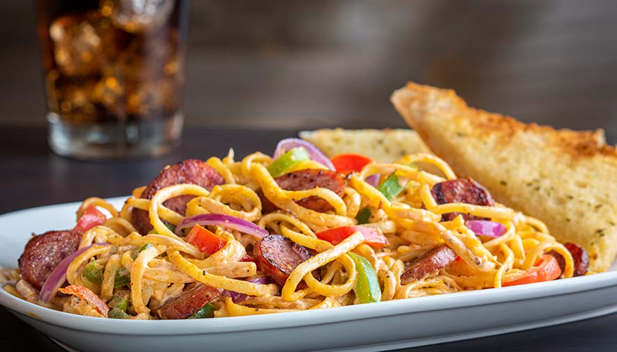 Plate of creamy pasta with sausage, peppers, and garlic bread from Smoky Mountain Pizzeria Grill.