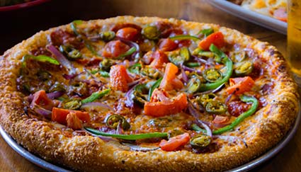 Pizza topped with tomatoes, peppers, onions, and jalapeños—perfect for Idaho catering events.
