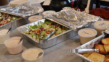 Catered salad, dressings, and cornbread from Smoky Mountain Pizzeria Grill on a table.