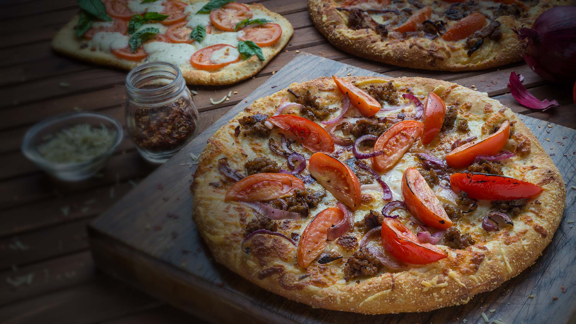 Sausage pizza topped with whole tomato slices served at Smoky Mountain Pizzeria & Grill in Idaho.
