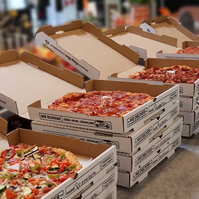 Several open Smoky Mountain Pizzeria Grill pizza boxes showcase Idaho catering favorites on a counter.