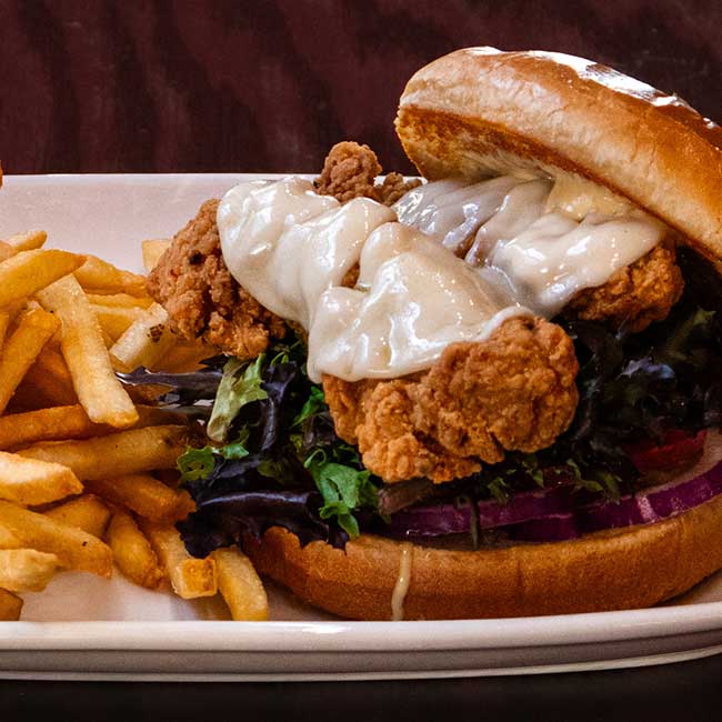 Fried chicken sandwich with melted cheese, lettuce, and fries at Smoky Mountain Pizzeria Grill.