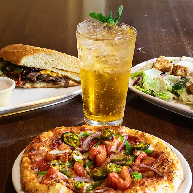 A pizza, sandwich, and salad from Smoky Mountain Pizzeria Grill on a wooden table in Idaho.
