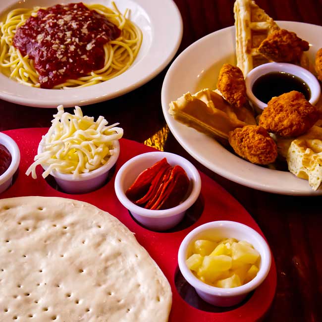 Uncooked Pizza crust with toppings, spaghetti, and chicken with waffles in an Idaho Banquet Room.