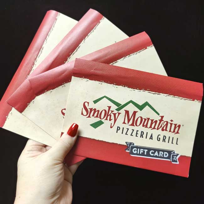 Hand holding three Smoky Mountain Pizzeria Grill gift cards—perfect for catering in Idaho.