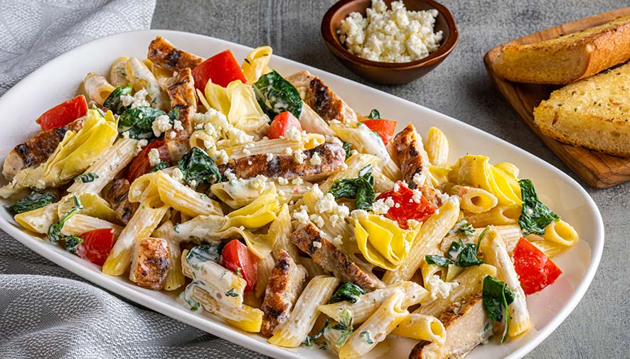 A plate of creamy penne pasta with grilled chicken, spinach, and feta cheese in Boise Idaho.